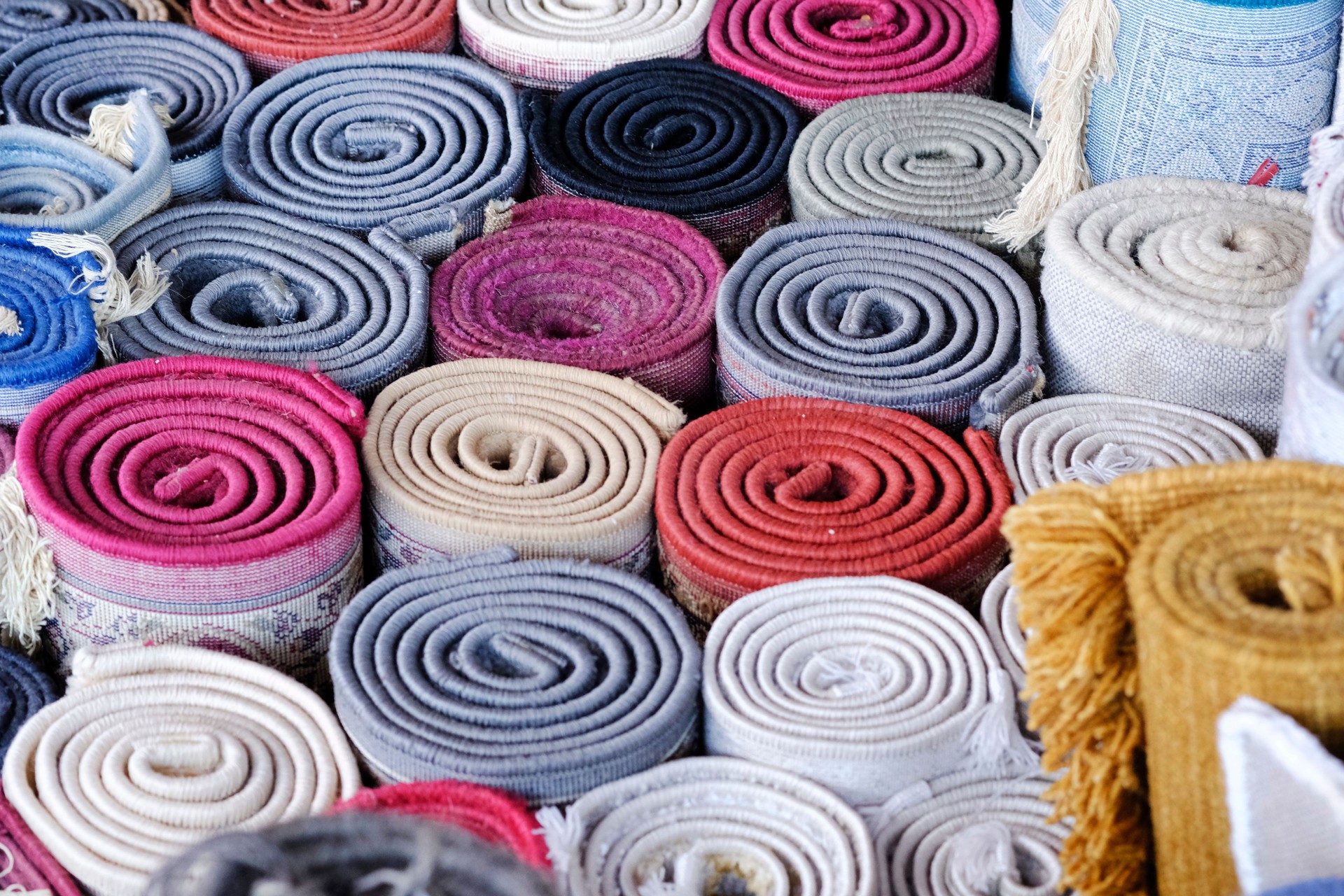 Stack of multicolored quality rugs at carpet shop, Carpets variety selection rolled up rugs shop store.